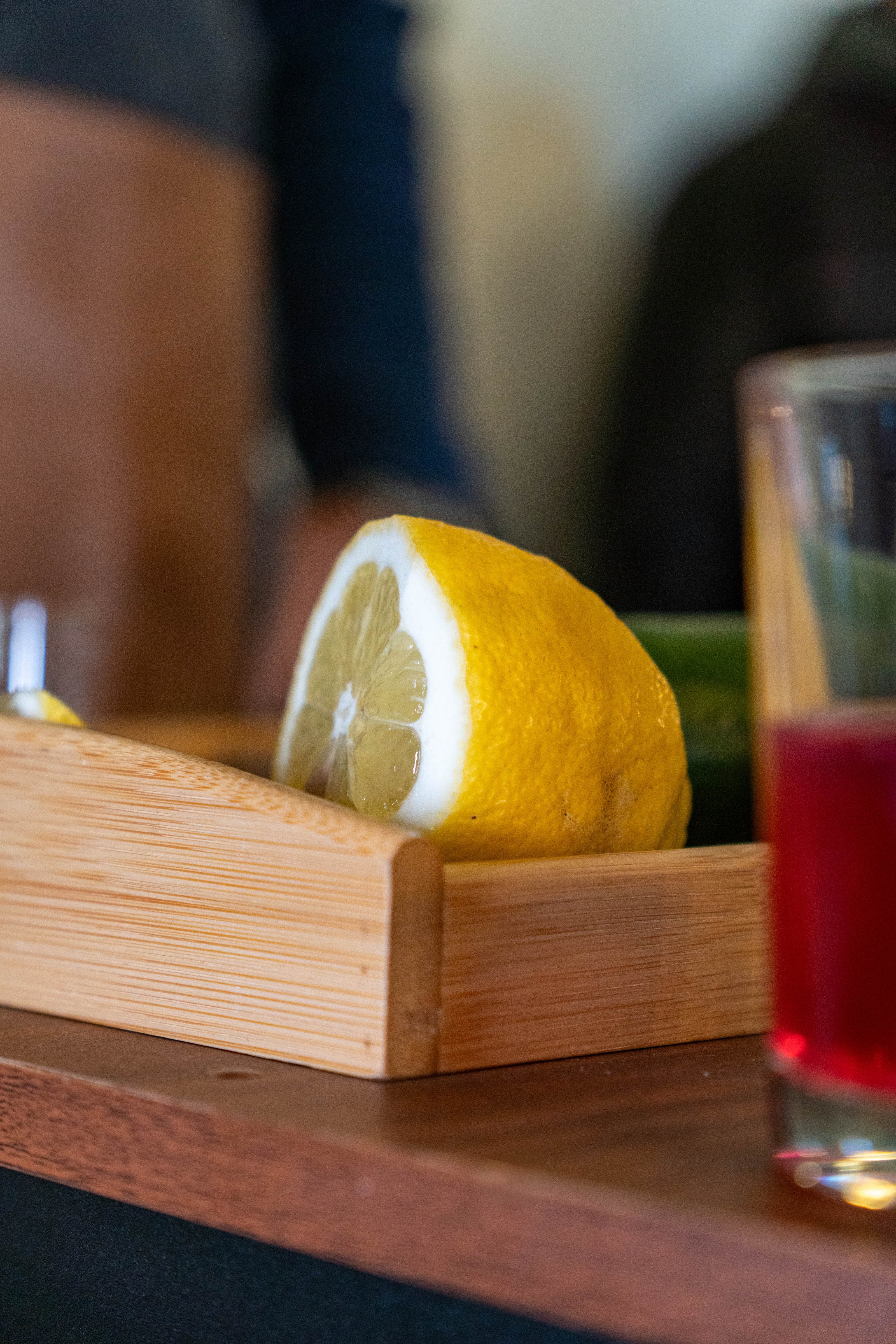 Nahaufnahme einer angeschnittenen Zitrone in einer Holzbox auf einem Tresen. Rechts im Bildrand ist ein Glas mit rotem Getränk sichtbar. Die Szene stammt vom Dresdner Feingeist Stand beim Hoffest.